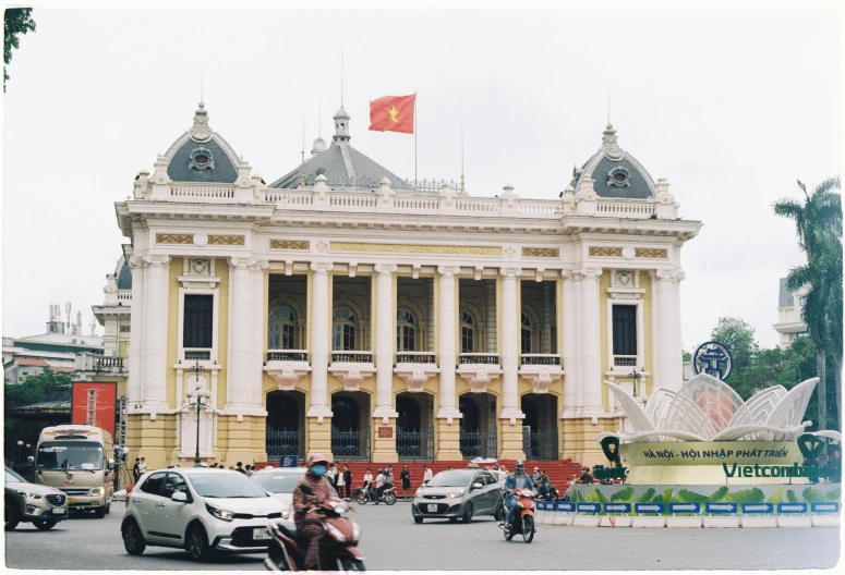 people on motorcycles near a large building with a flag on top