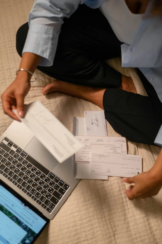 two people sit with mail and open laptop