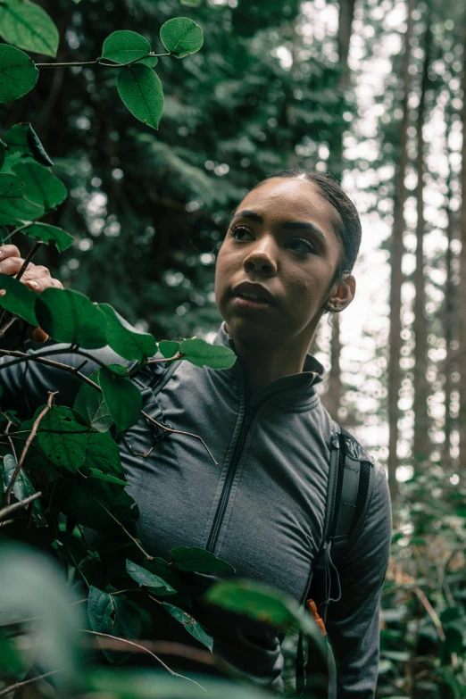 woman wearing athletic clothes stands in a clearing, amongst many trees