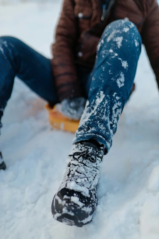 a person sitting in the snow, with their feet propped up