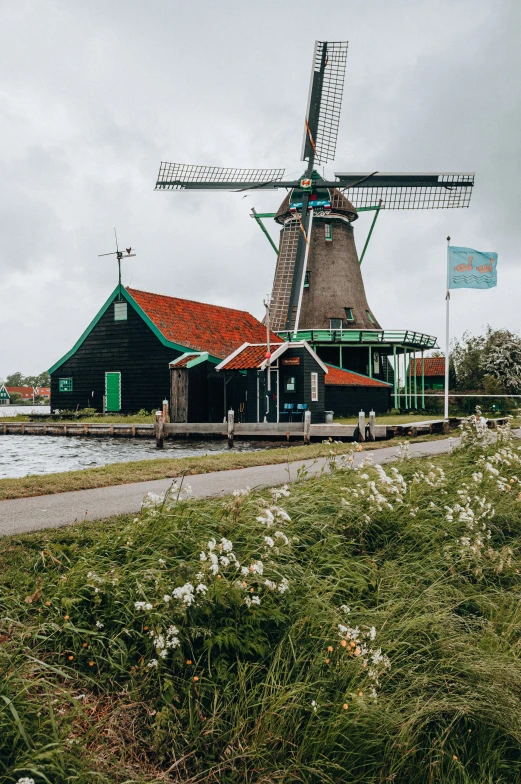 windmill sitting near the water and other buildings