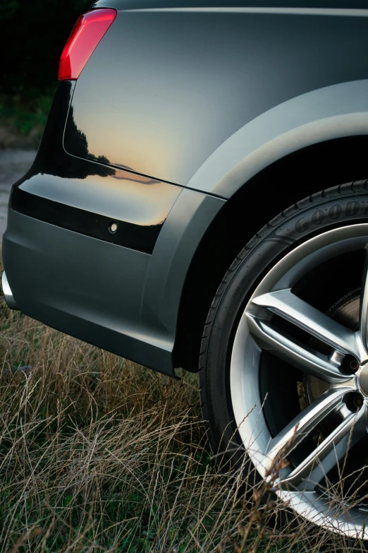 a close up of a car's wheel with grass in the foreground