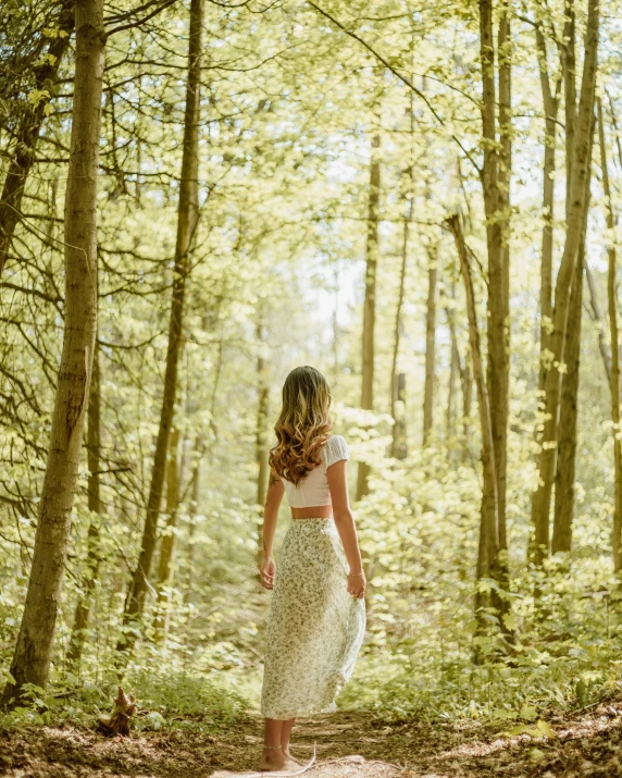 a woman walking down a dirt road in the woods