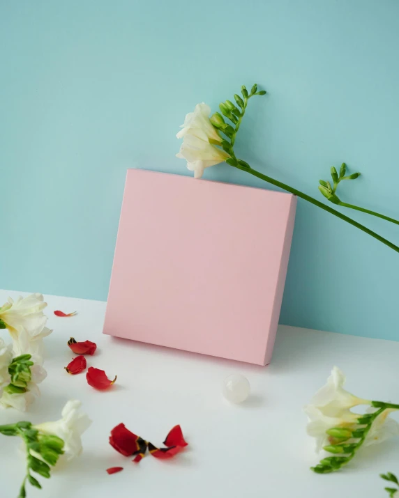 an empty pink paper box with white and red flowers laying around