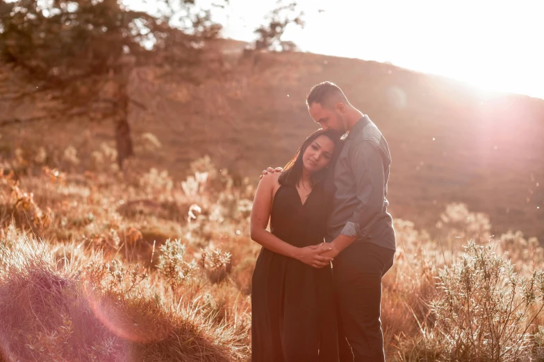 the young couple are posing in front of trees