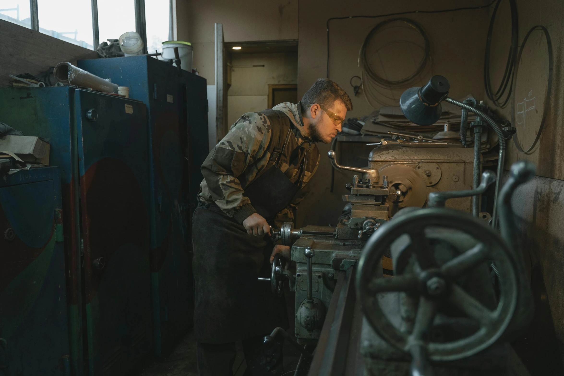 man using milling machine inside of workshop for metalworking