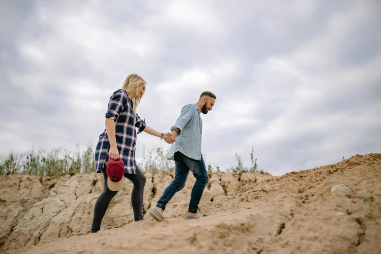 a woman holding hands with a man on top of a cliff