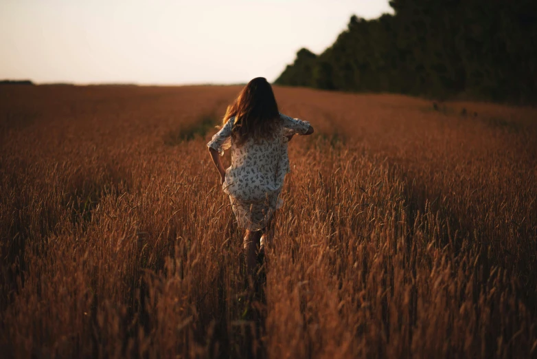 a girl walking through tall brown grass