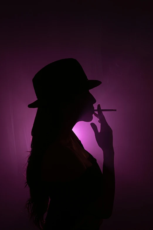 a dark woman in a hat holding a cigarette