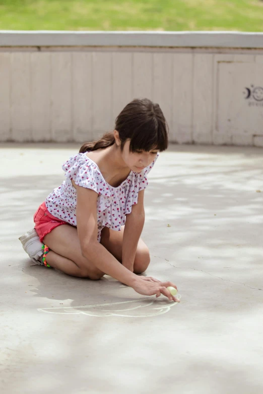 a girl squatting down on a stone floor, holding an apple