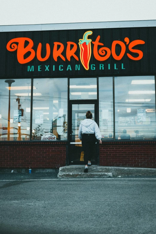 a man walking out the entrance of burrito's mexican restaurant