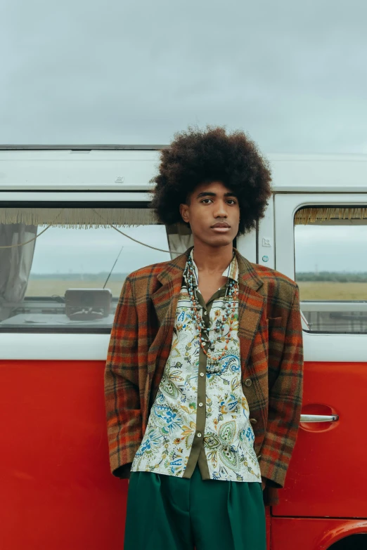 an individual posing near an orange van on a gray day