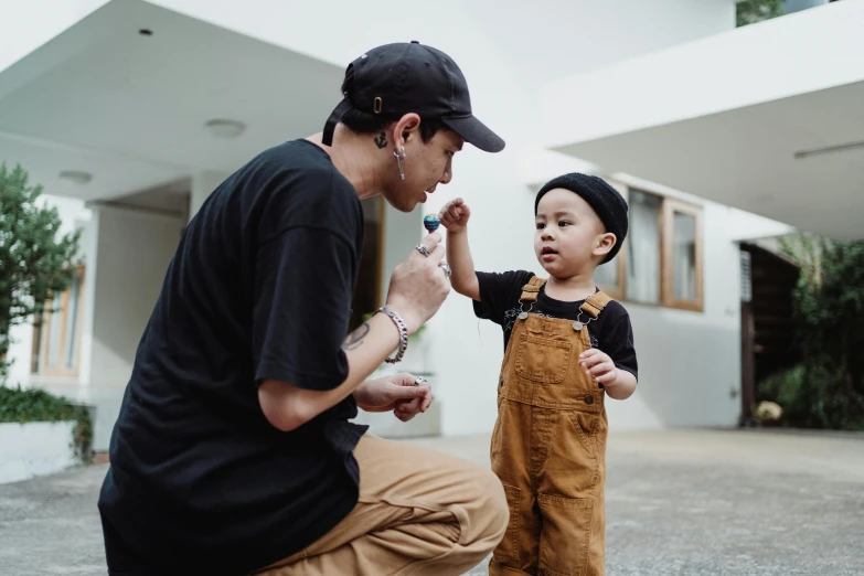 a man with a cap on is talking to a little boy