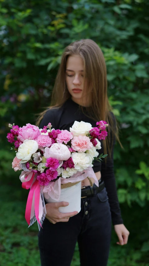 woman holding a bouquet of flowers standing in front of bushes