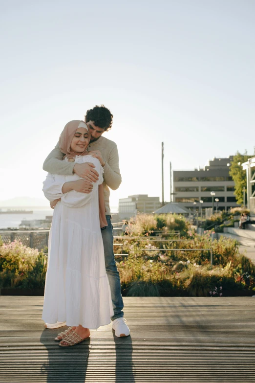 the woman is hugging her man while he is standing outside