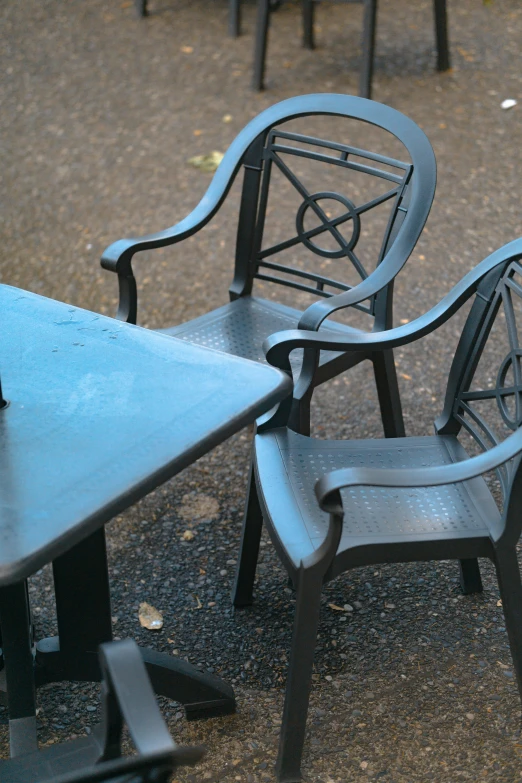 two black wooden chairs sitting in the middle of a pavement area