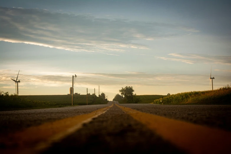 the view from inside the vehicle of a road passing over windmills