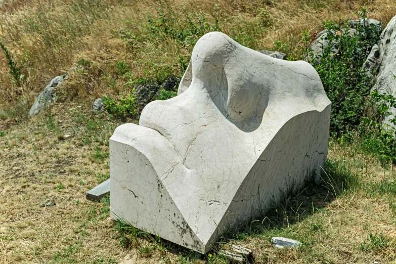 a white stone sculpture sits next to some rocks