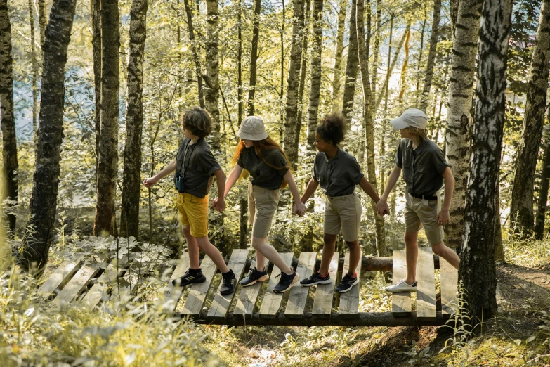 three children wearing shoes walk along a wooden path