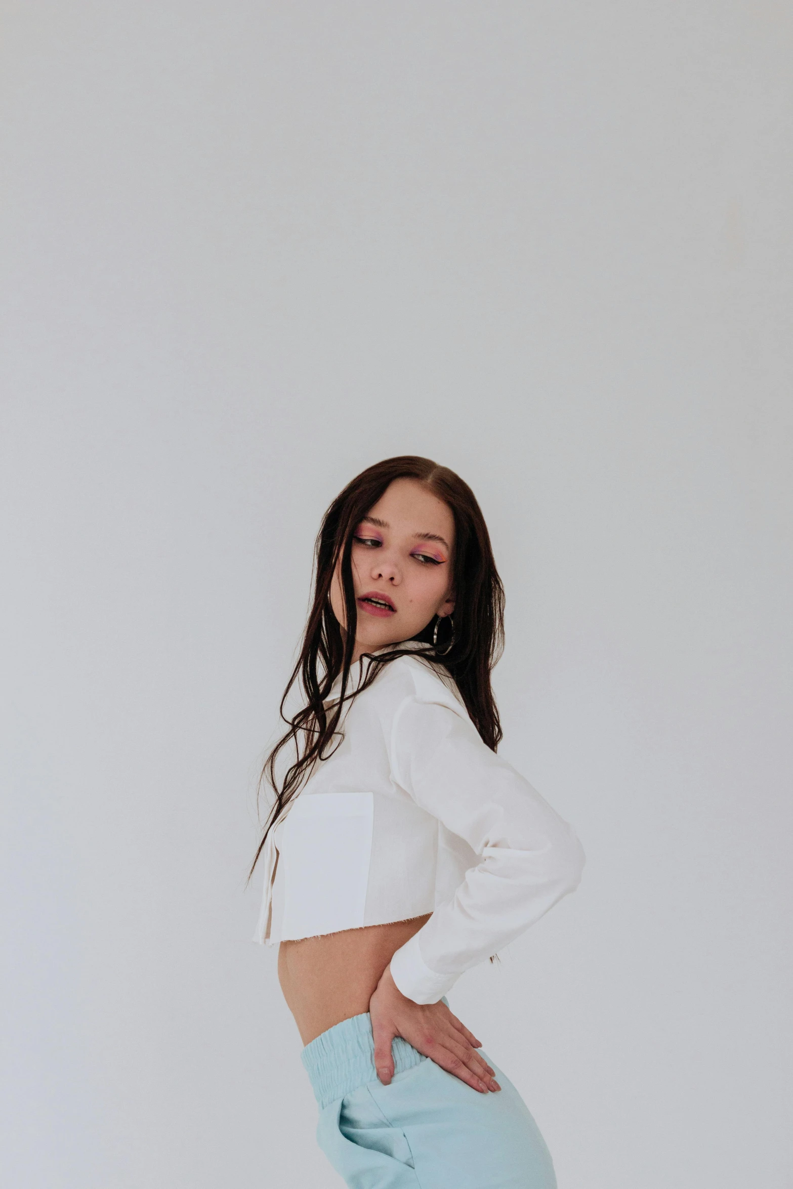 woman looking at herself while standing in a white room