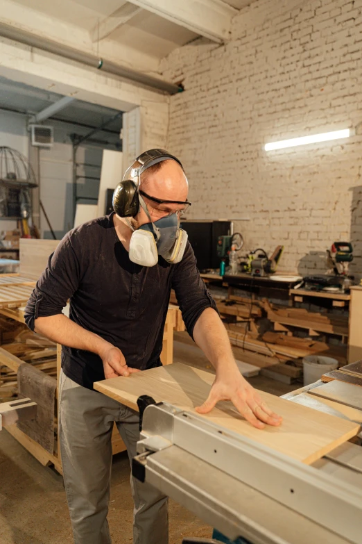 a man in head phones making furniture out of wood