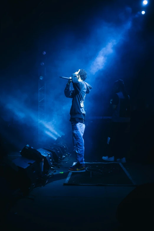 a man is singing on stage at night with lights coming off