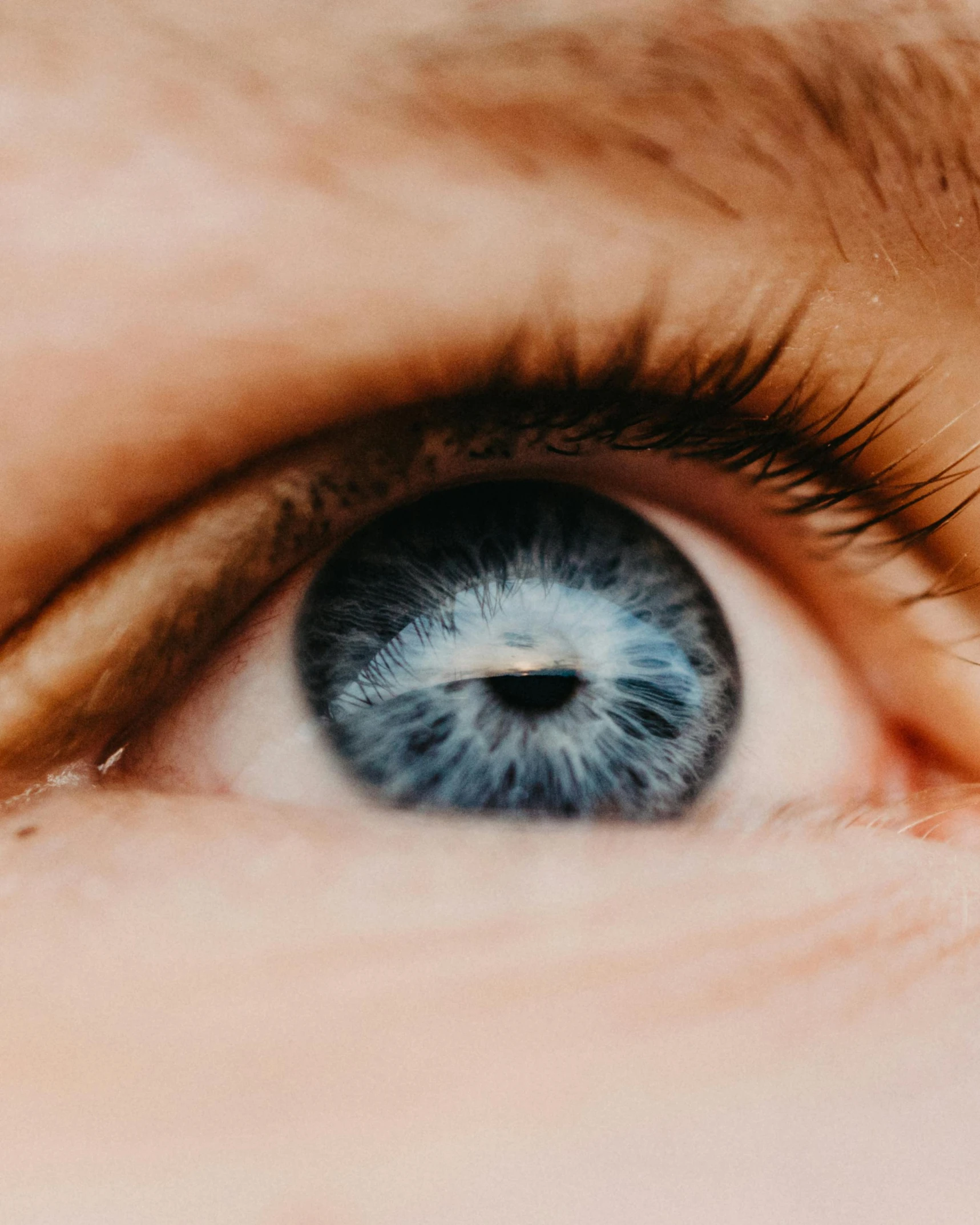 an open eye shows the blue iris of a persons blue colored iris