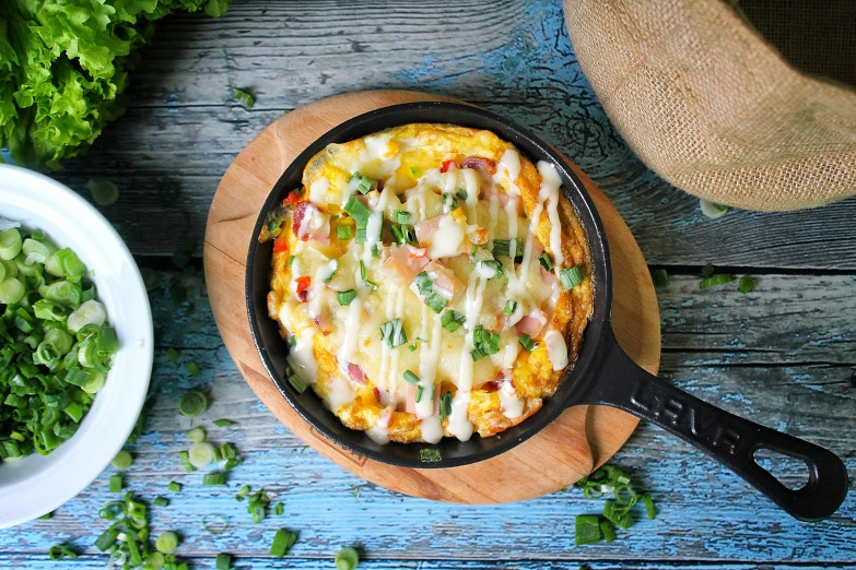 a pizza covered with cheese and toppings sits in a cast iron set