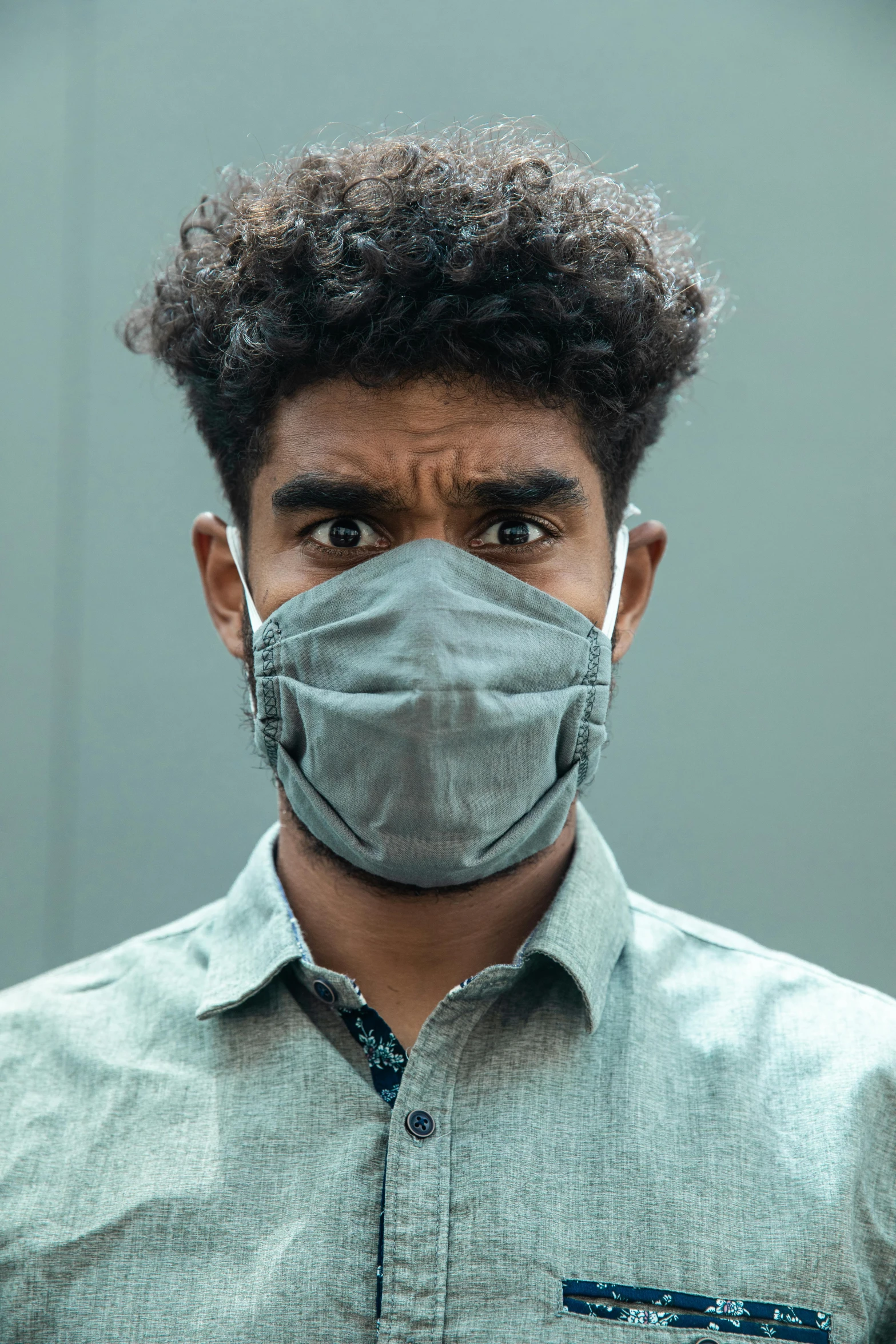 a man wearing a surgical mask and looking straight ahead