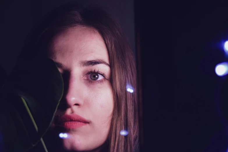 a young woman looking away from the camera with a blue light on her