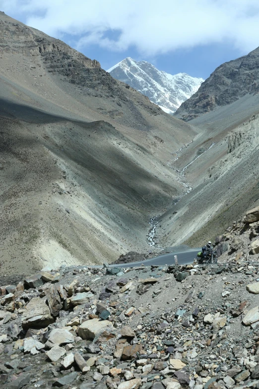 a man riding his bicycle on top of a rock covered hill