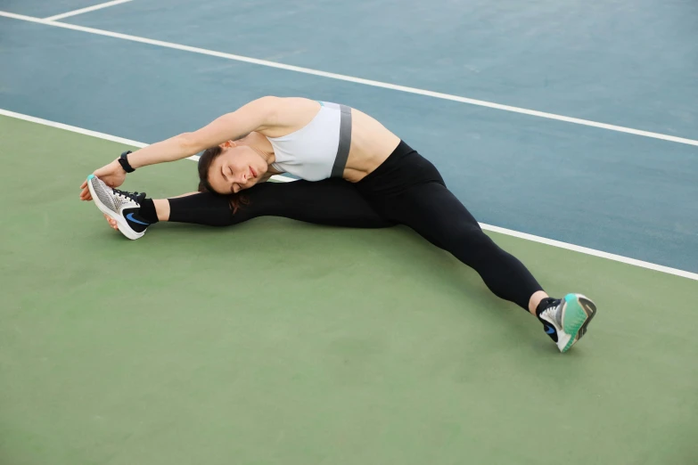 a woman that is laying down on a tennis court