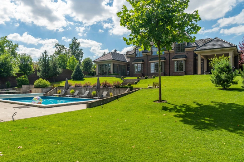 a backyard with an in ground pool and several lounge chairs