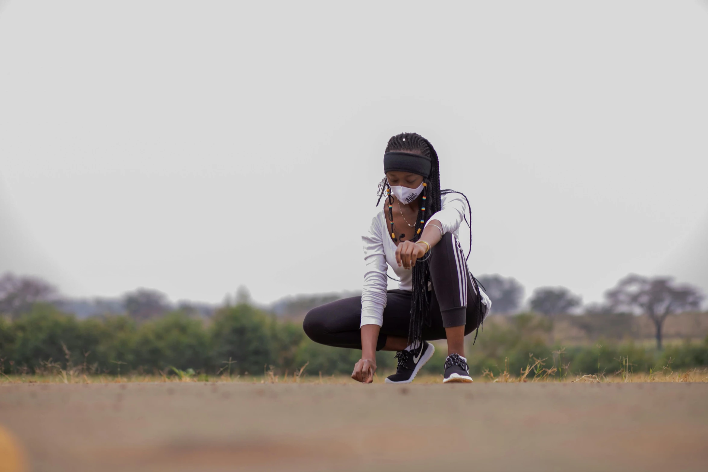 woman crouches down with her hands together as she has a mask on