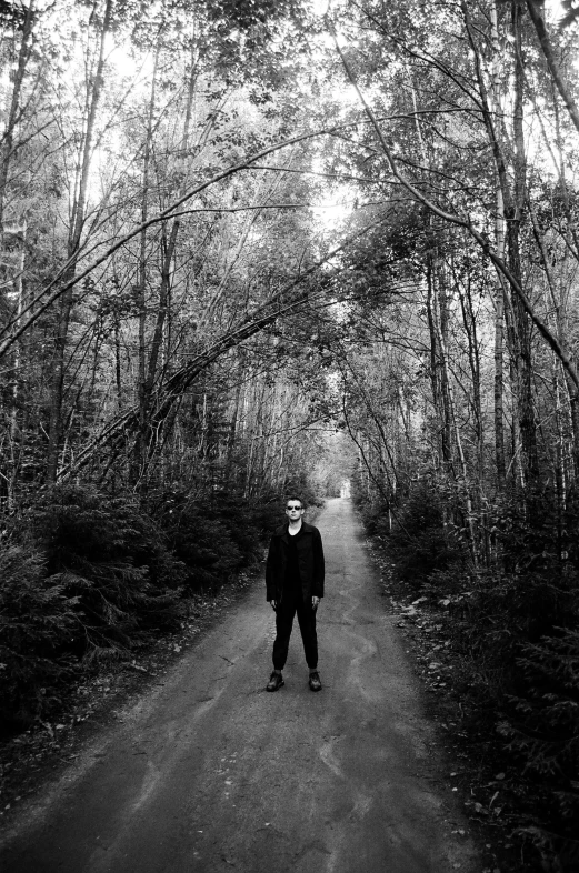a man walking down a trail lined with trees