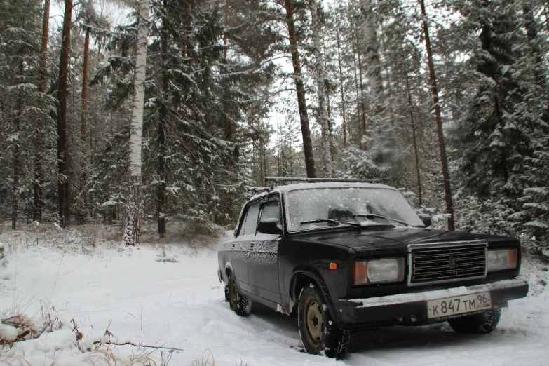 a car is sitting in the snow among a forest