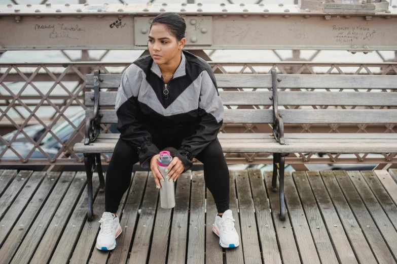 a woman sitting on a bench in front of a bench with her feet on the ground