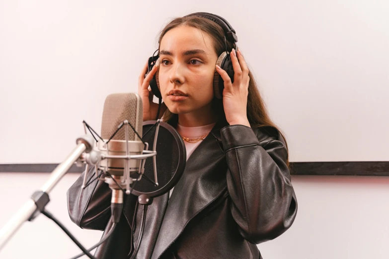 a woman standing in front of a microphone with headphones on her ears