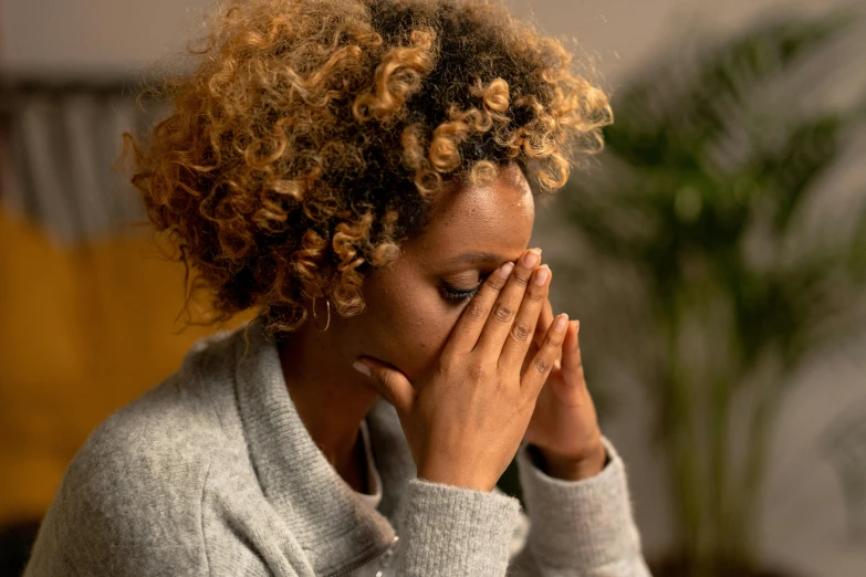 a woman covering her face with hands while looking off into the distance