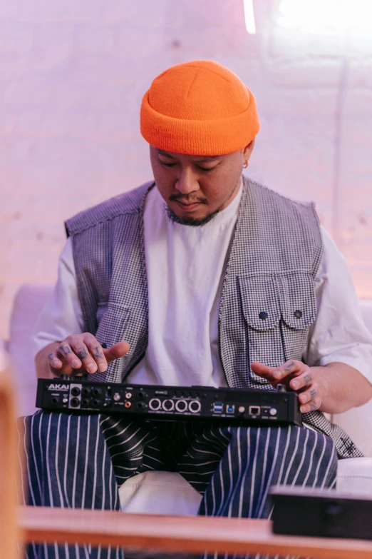 a man wearing an orange beanie sitting in a chair