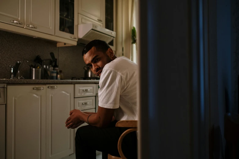 a man sits in his kitchen at the sink