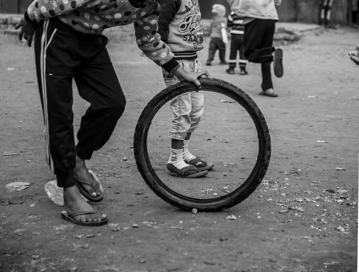 several people standing around playing with a tire