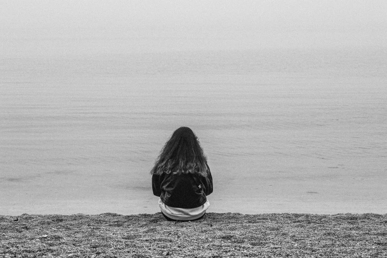 the back end of a person kneeling near a body of water