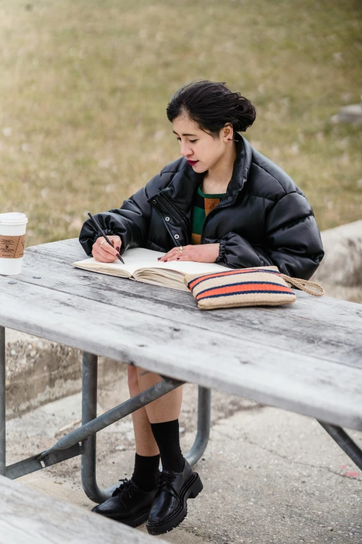 a person sitting at a picnic table and writing