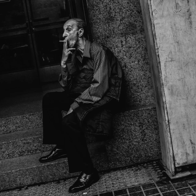 a man in business attire is leaning against a wall