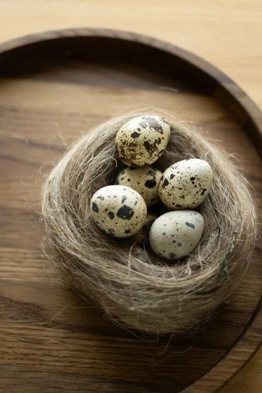 four quail sitting in a brown bowl on a wooden table