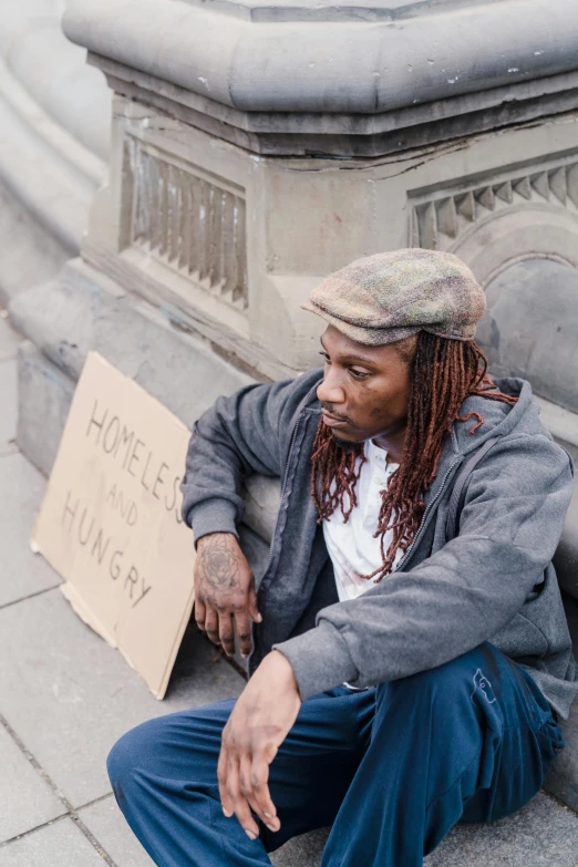 a young black man holding a homeless sign