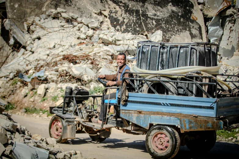 a man riding in an old pickup truck with a load