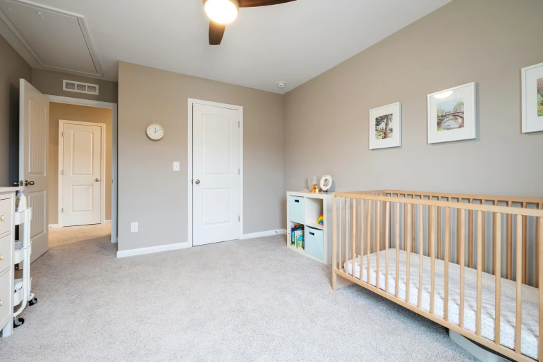 a nursery room with gray carpet and white crib