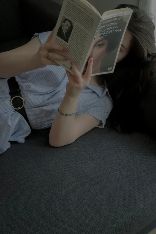 a woman reading a book on the sofa